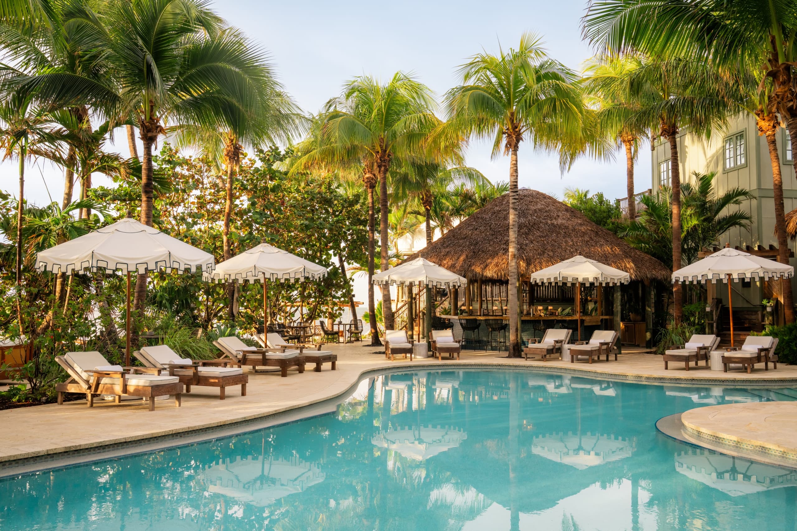 The outdoor swimming pool, cabanas, and tiki bar at Little Palm Island Resort