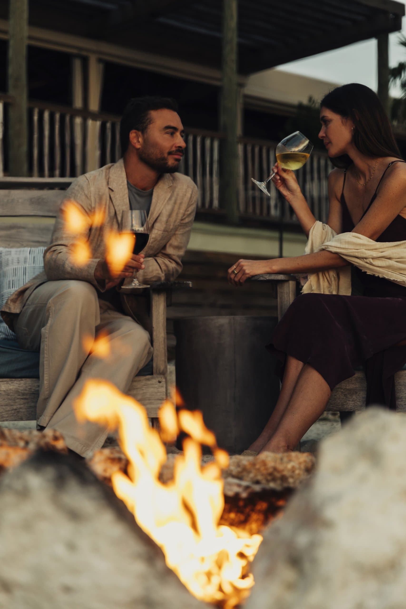 A couple drinking wine by an outdoor fire pit outside their suite at Little Palm Island Resort.