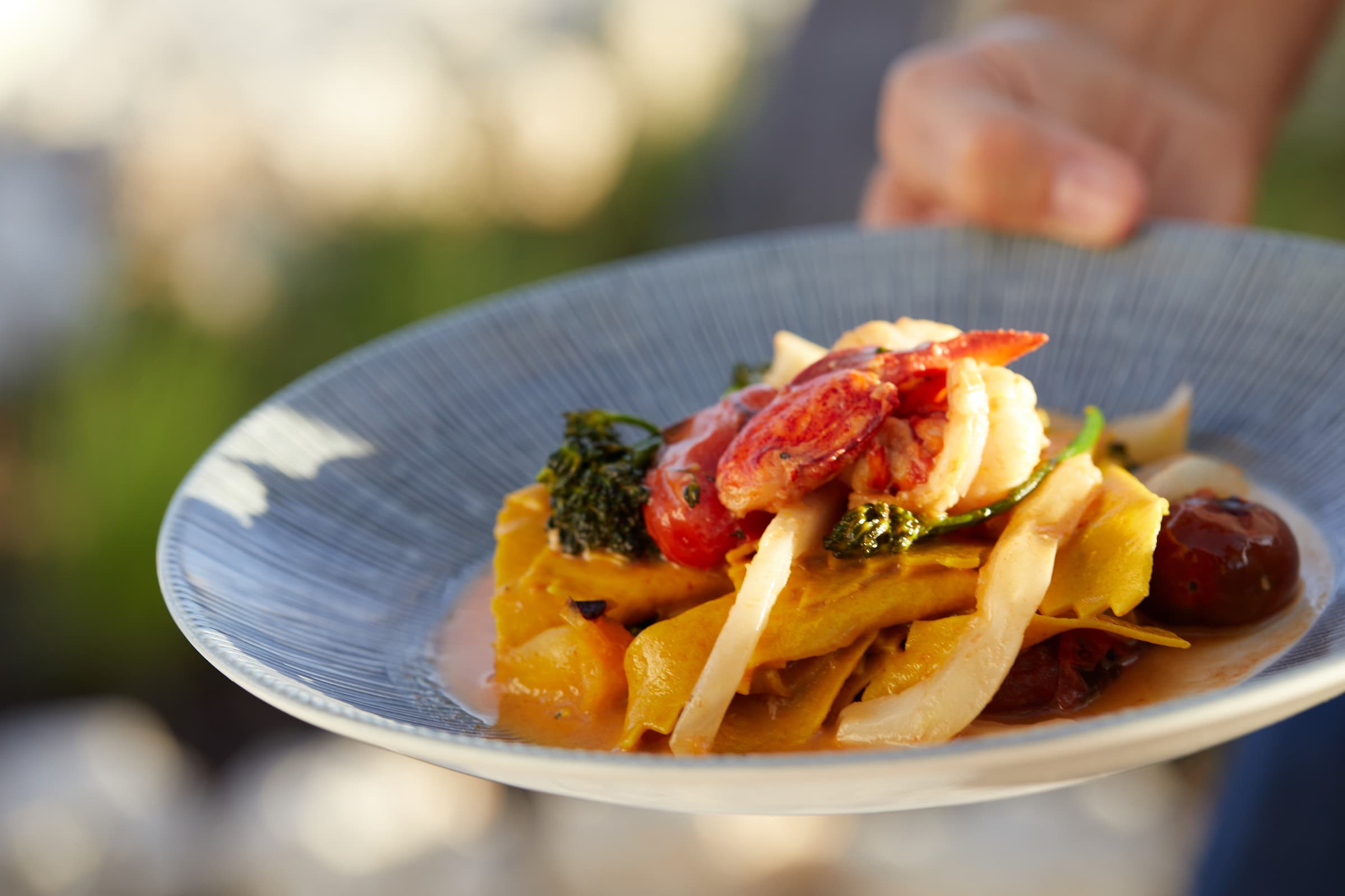 A server bringing over a plate of food from the restaurant of Little Palm Island Resort