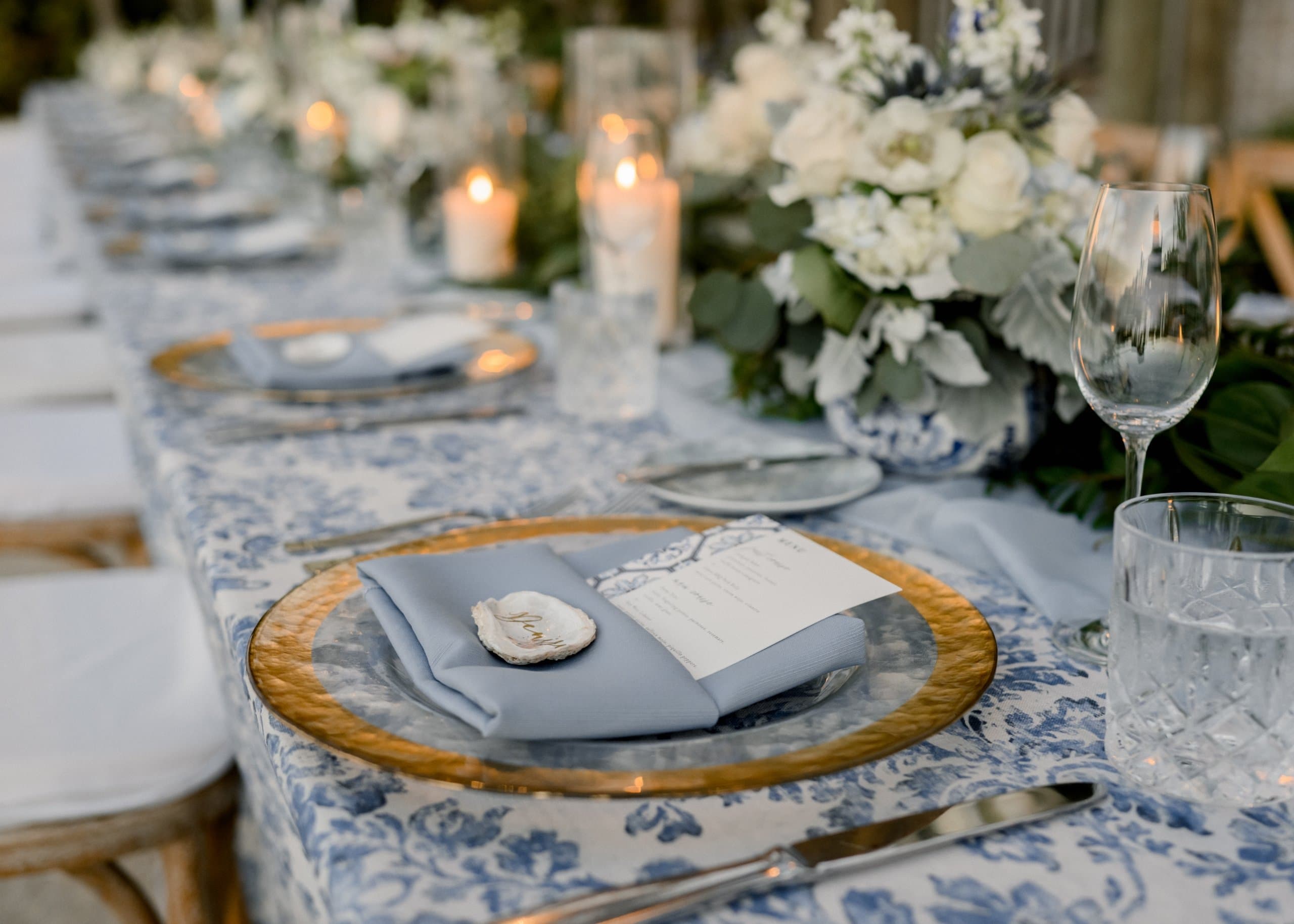 A long elegant dining table set for a luxury event and decorated with candles and flowers.