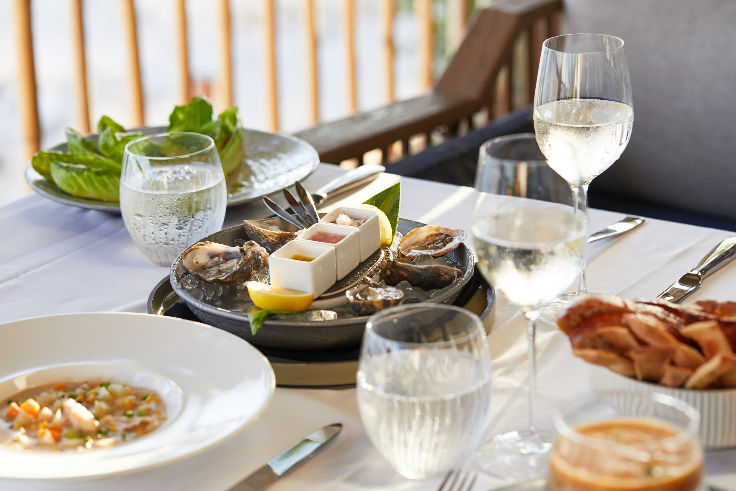 A table with oysters, chowder and glasses of water and wine.