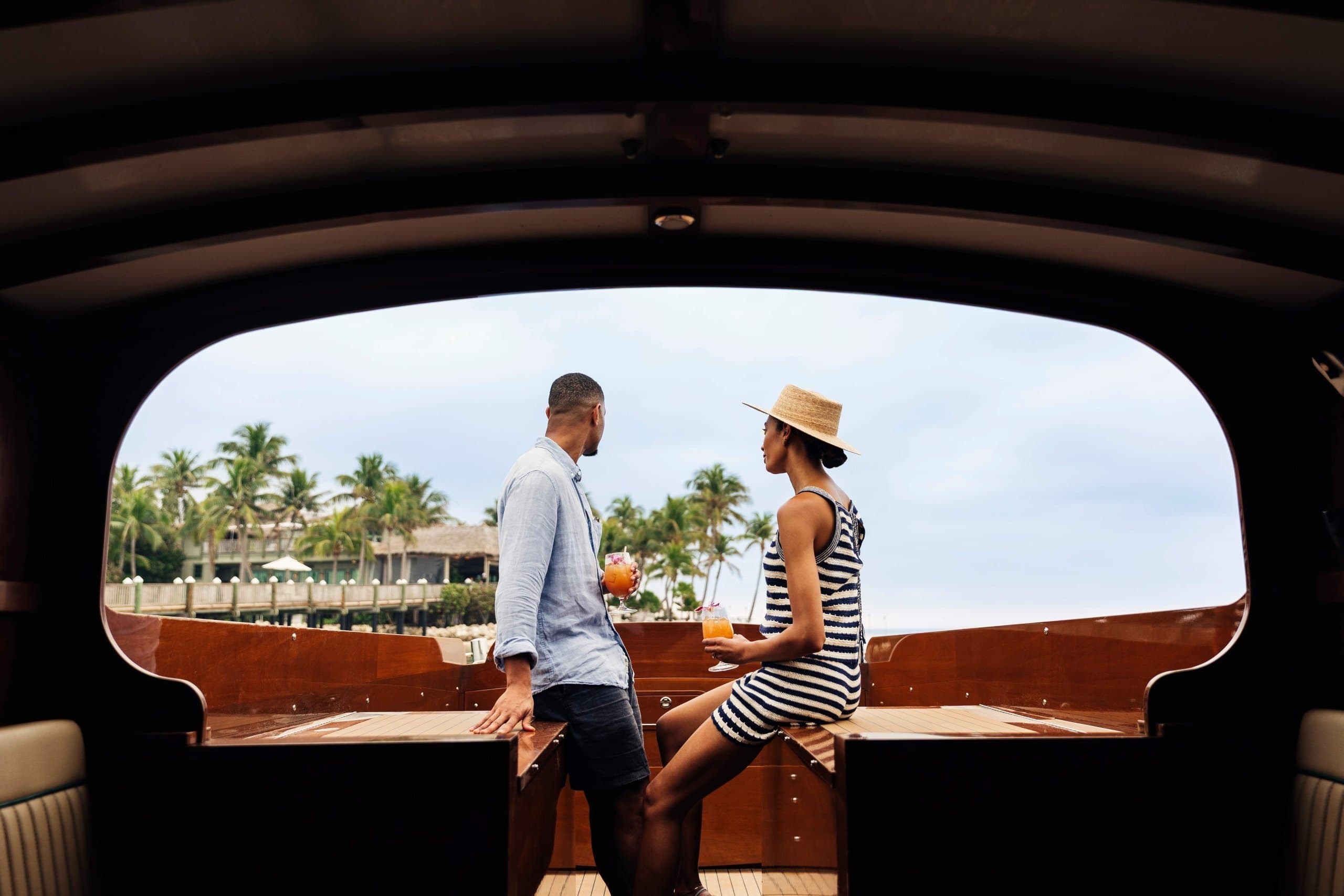 A couple drinking cocktails on a yacht by Little Palm Island Resort's private marina.