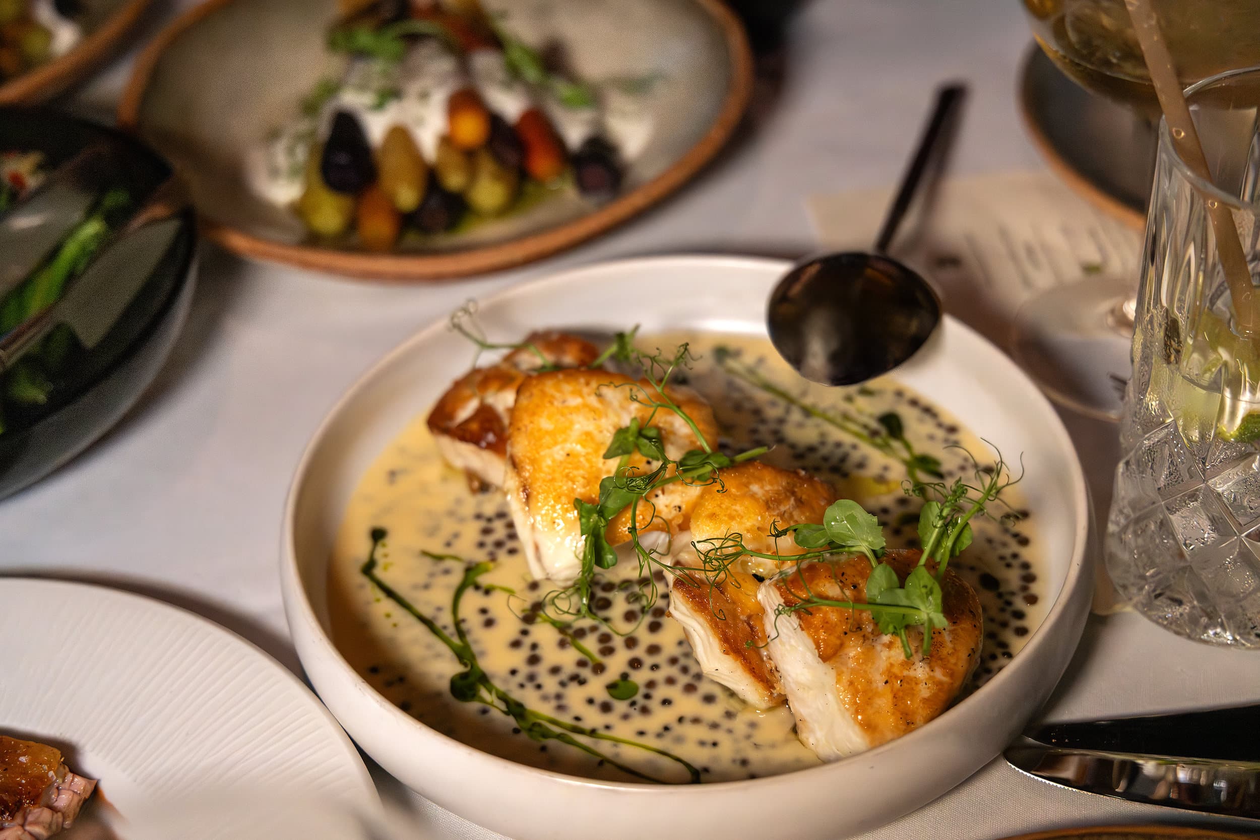 Pan-seared white fish fillets in a creamy caviar beurre blanc with pea shoots, served at Little Palm Island Resort & Spa in the Florida Keys