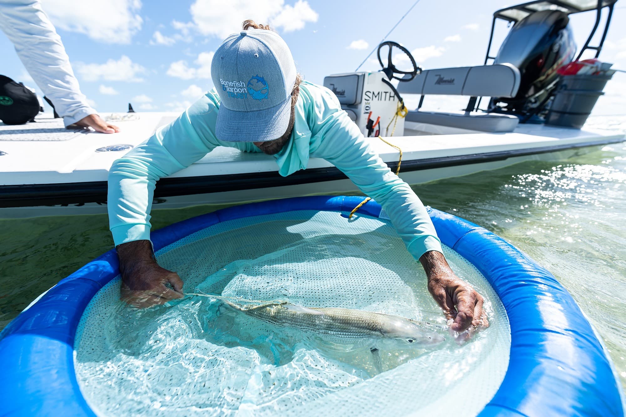 Marine biologist releasing a tagged bonefish into the clear waters off Little Palm Island, Florida Keys