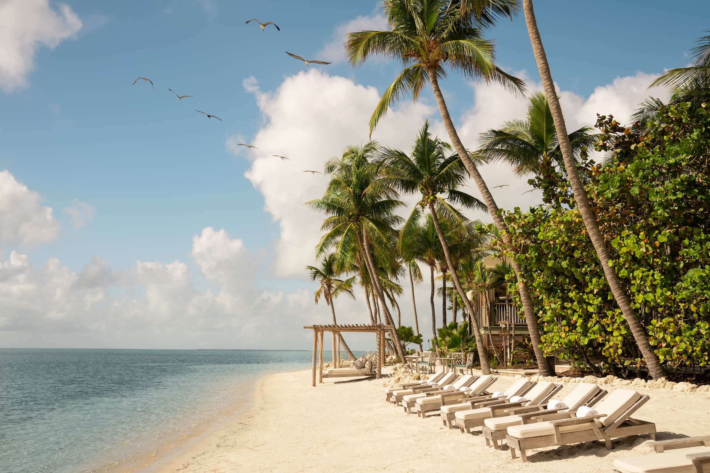 Cabanas in a row on the beach at Little Palm Island Resort