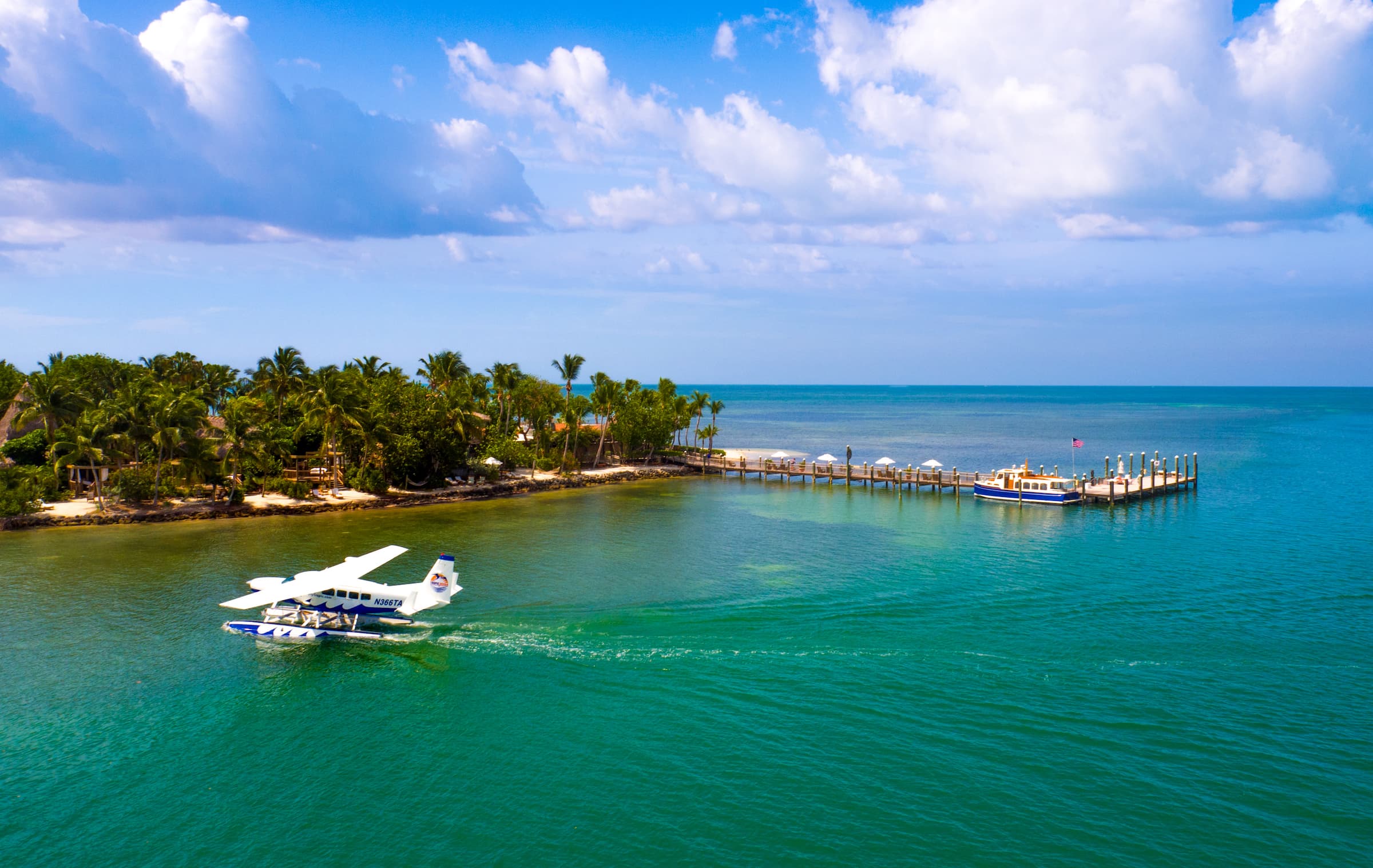 The Marina at Little Palm Island Resort with an arriving seaplane landing on the water
