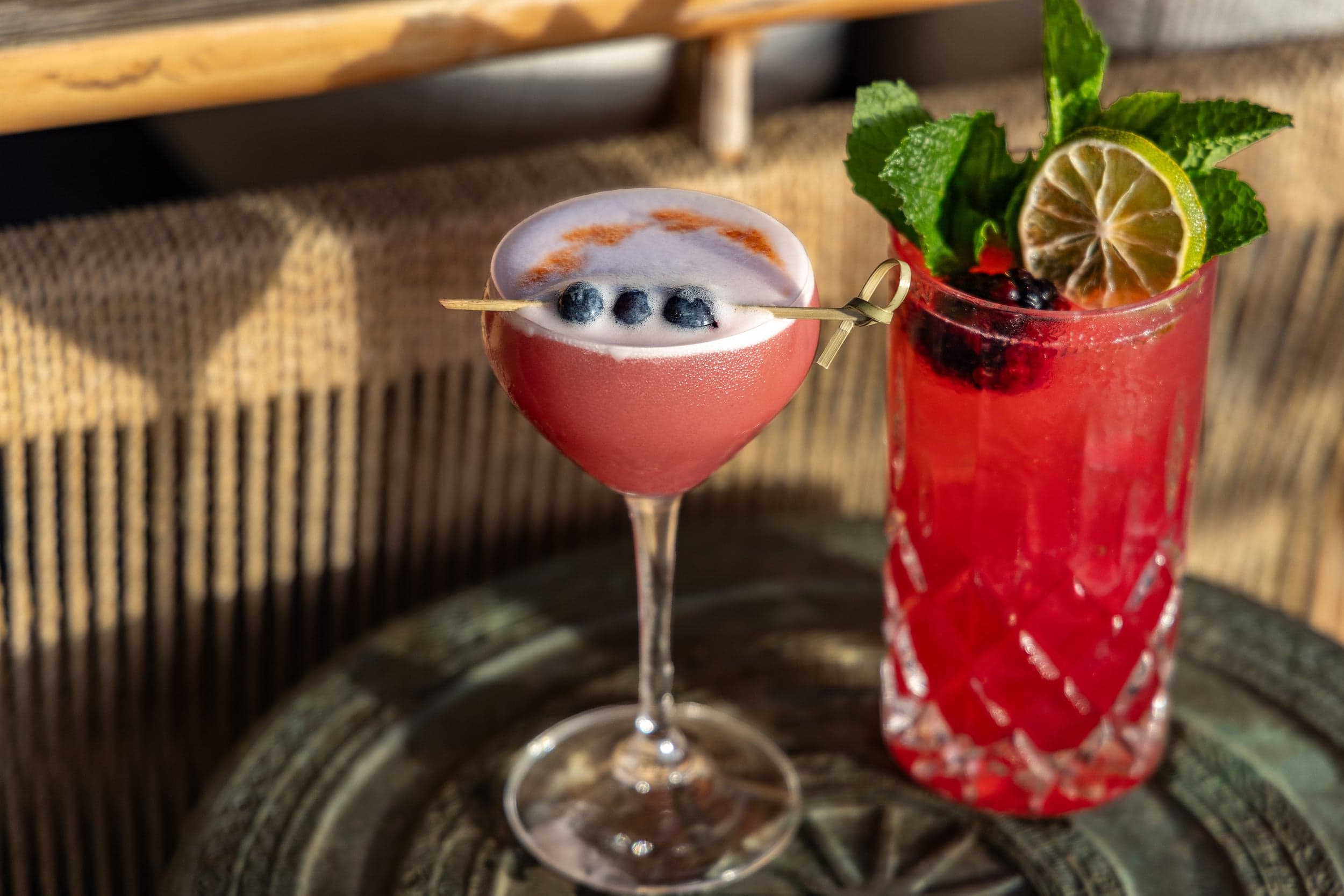 Blueberry-garnished sour cocktail in a coupe and a mint and blackberry highball with dried lime at Little Palm Island Resort & Spa in the Florida Keys