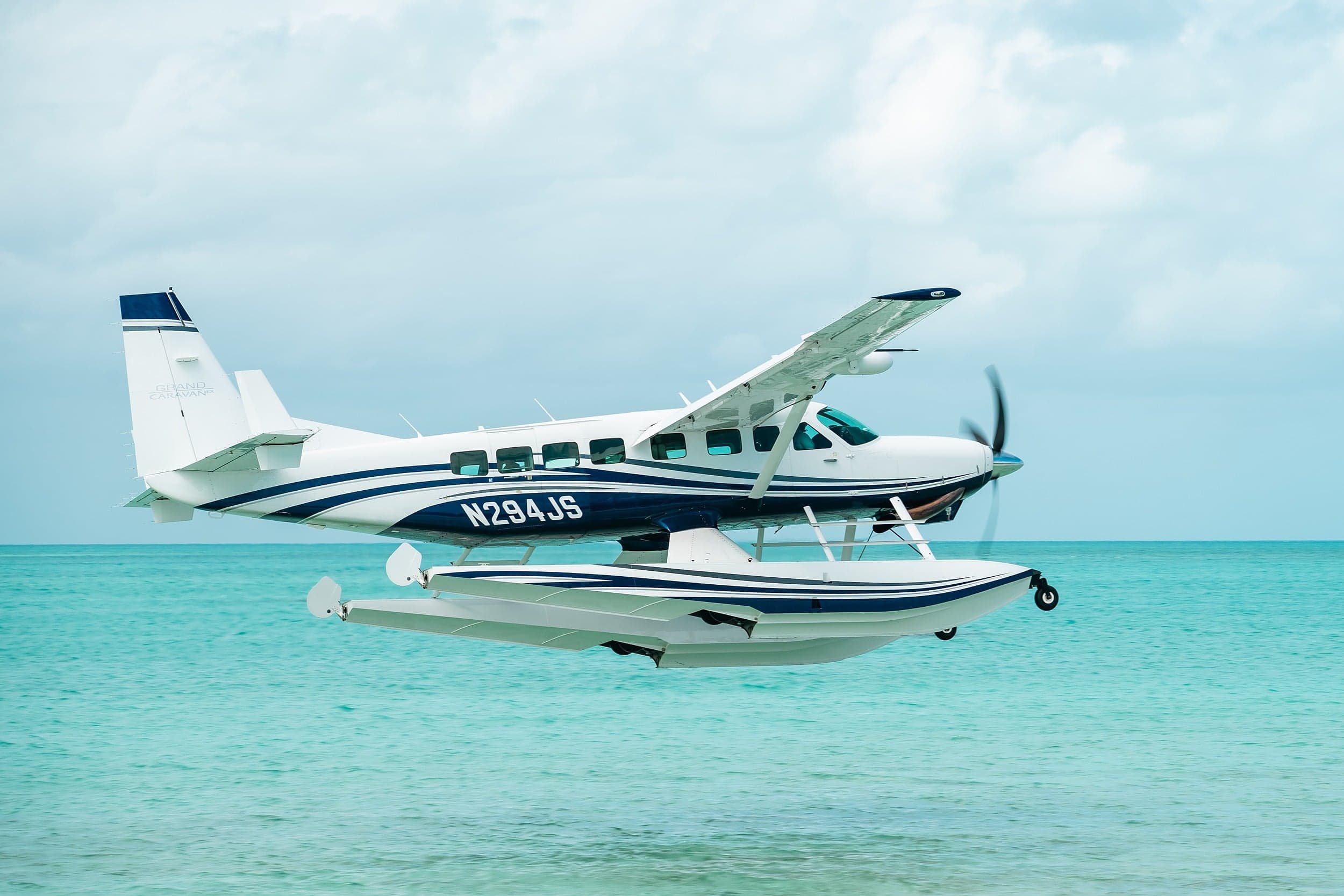 flyExclusive Cessna Grand Caravan seaplane flying low over turquoise Florida Keys water on approach to Little Palm Island resort