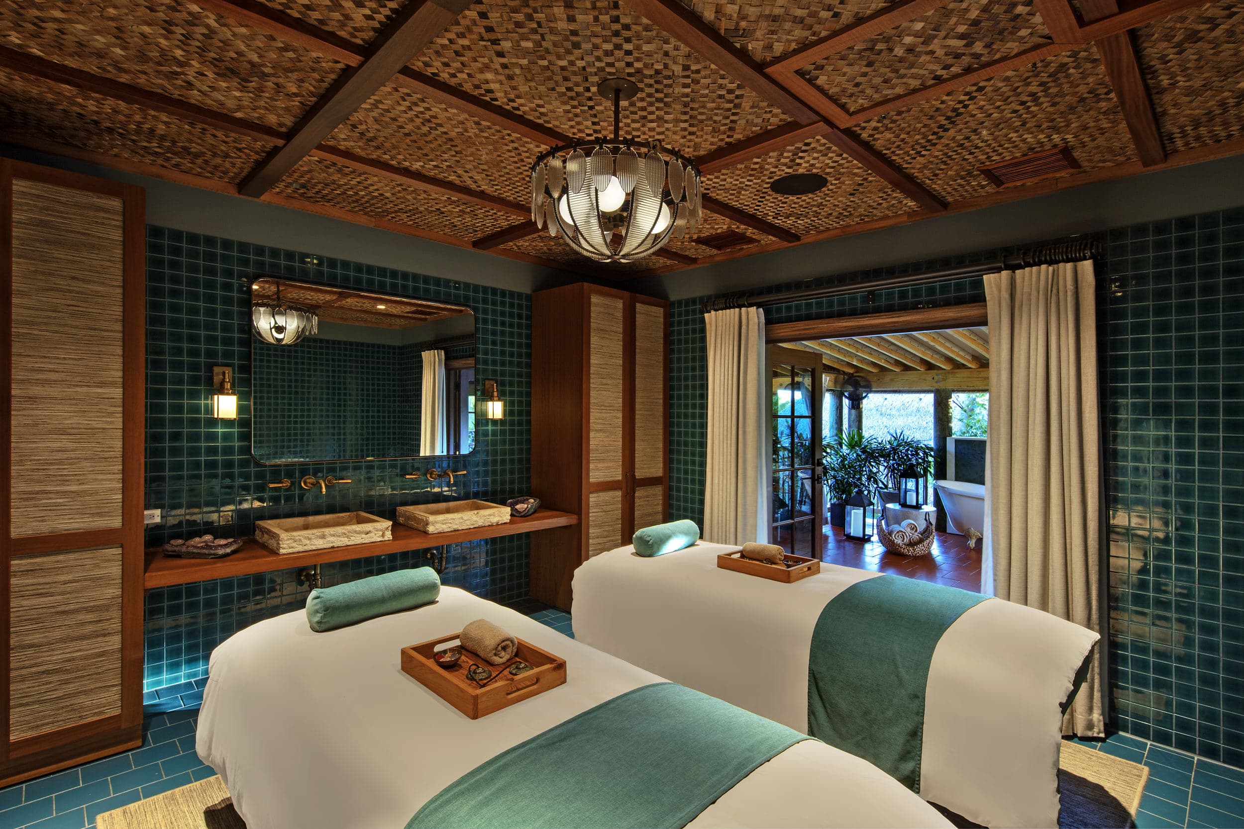 Couples spa treatment room with twin massage tables, teal tile walls and a woven ceiling opening onto a private soaking tub — Little Palm Island Resort & Spa, Florida Keys