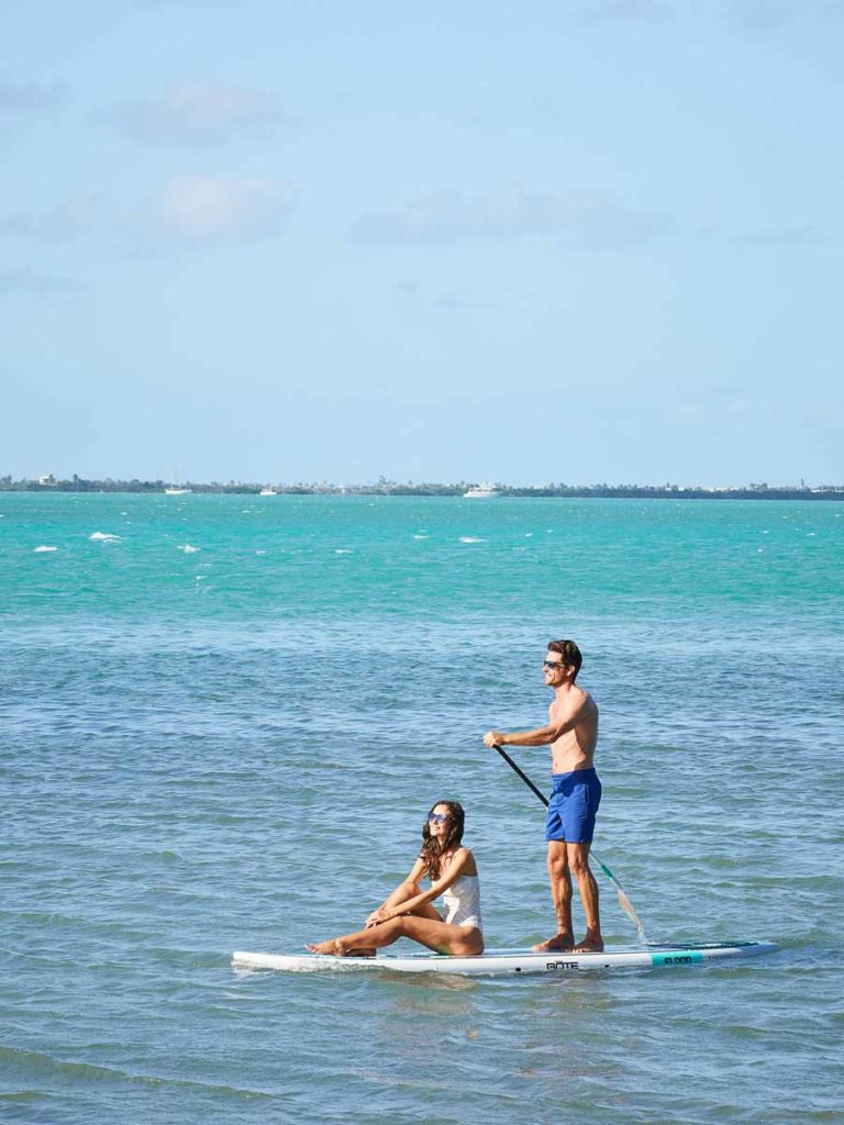 Couple in the ocean on a paddleboard.